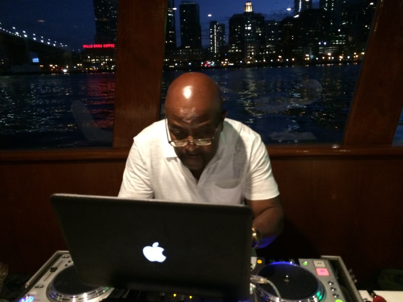 DJ Afrique performing on a boat with the San Francisco skyline illuminated at night