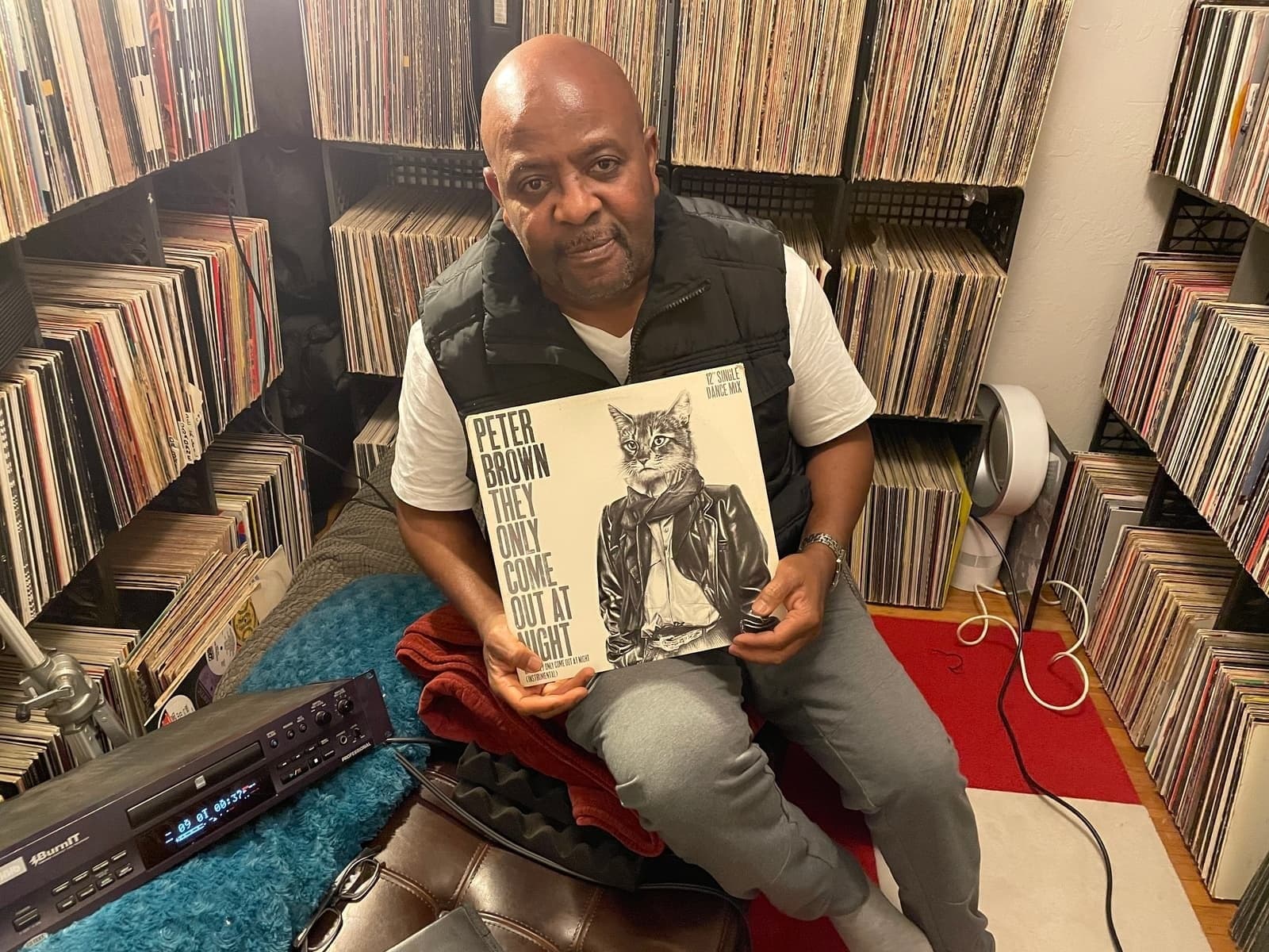 Alex in his vinyl room holding a record, surrounded by his massive collection